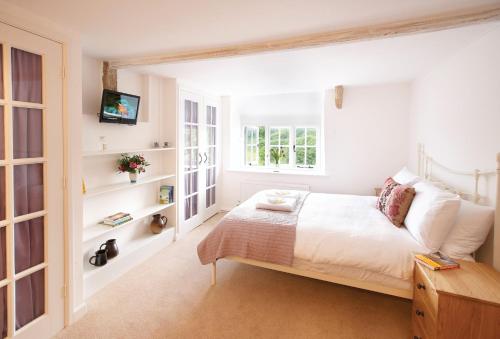 a bedroom with a bed and a tv on a wall at Rose Cottage Dorset in Powerstock