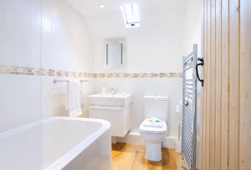 a bathroom with a toilet and a tub and a sink at Rose Cottage Dorset in Powerstock