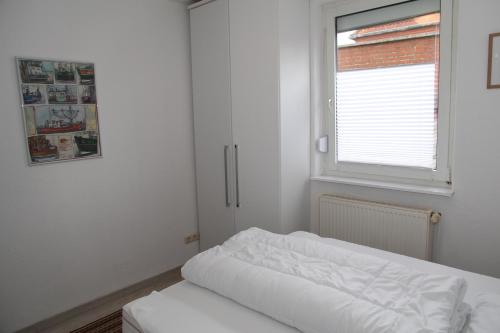 a white bedroom with a bed and a window at Jan Dollart 1 in Greetsiel