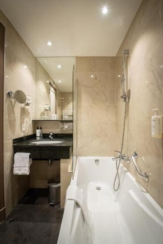 a bathroom with a bath tub and a sink at Splendid Hotel & Spa Nice in Nice
