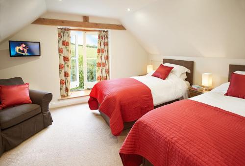 1 dormitorio con 2 camas, sofá y ventana en Rampisham Hill Farm Barn, en Hooke