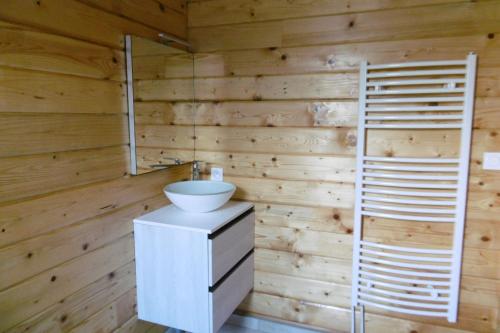 a bathroom with a white sink and a wooden wall at Chalet écologique en campagne bazadaise in Saint-Côme