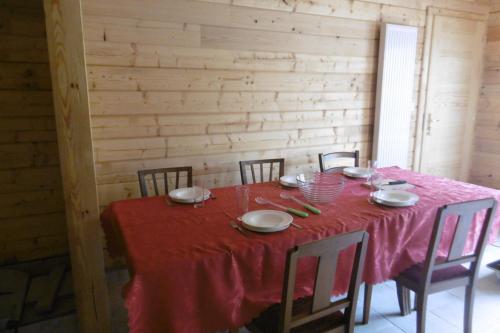 a dining room table with a red table cloth and chairs at Chalet écologique en campagne bazadaise in Saint-Côme