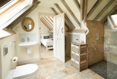 een badkamer met een toilet, een wastafel en een spiegel bij Furlong Barn in Southam