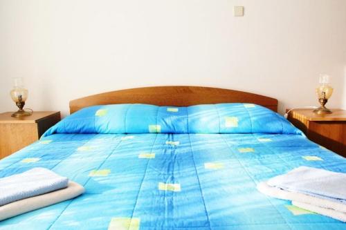 a blue bed with a blue comforter and two night stands at Apartment M in Seget Vranjica