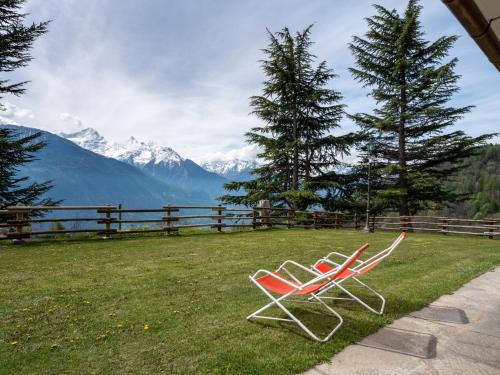 due sedie sedute sull'erba con montagne sullo sfondo di Apartment Renard by Interhome a Sarre