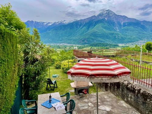 a patio with a table and an umbrella and mountains at Apartment Cà del Fritz by Interhome in Sorico