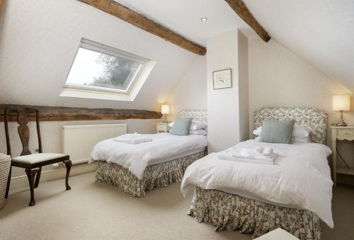a attic bedroom with two beds and a window at Coach House Hawling in Hawling