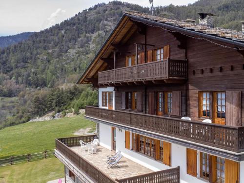 a large wooden house with a balcony and mountains in the background at Apartment Chaouette by Interhome in Sarre