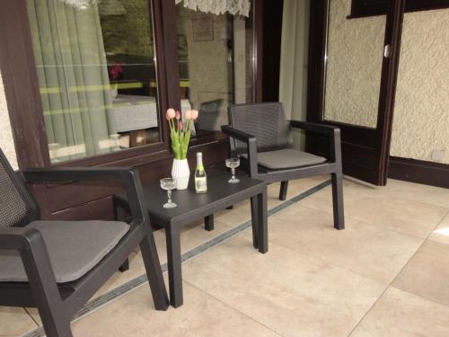 Duas cadeiras e uma mesa com copos de vinho e flores em Apartment Sun & Mountain View by Interhome em Bad Hofgastein