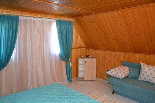 - une chambre avec un canapé bleu et une fenêtre dans l'établissement Cabana Timeea, à Ostrovu Corbului