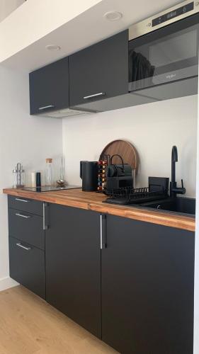 une cuisine avec des armoires noires et un comptoir dans l'établissement Maison Divon, à Montagne
