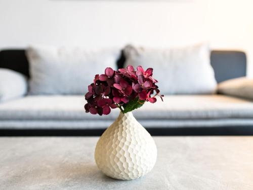 um vaso branco com flores roxas em cima de uma mesa em Apartment A601 by Interhome em Lahnstein