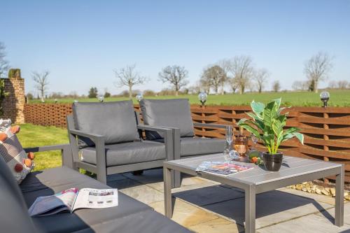 a patio with two chairs and a table at Thatch Barn in Lingwood