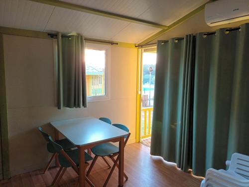 MontrásにあるCamping Relax Geのテーブルと椅子、窓が備わる客室です。