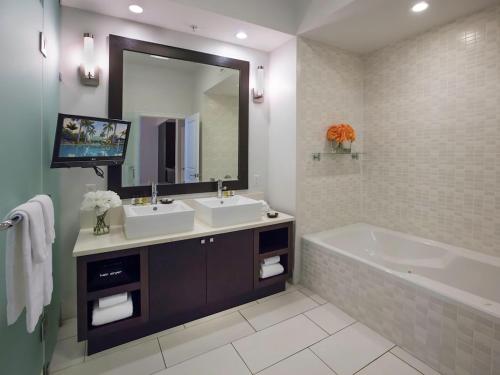 uma casa de banho com 2 lavatórios, uma banheira e um espelho. em Apartment Provident Doral at The Blue-7 by Interhome em Miami