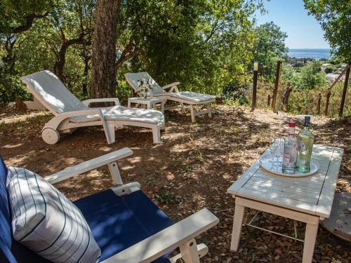- un groupe de chaises et une table avec une bouteille de vin dans l'établissement Holiday Home La Planquette by Interhome, à Cavalaire-sur-Mer
