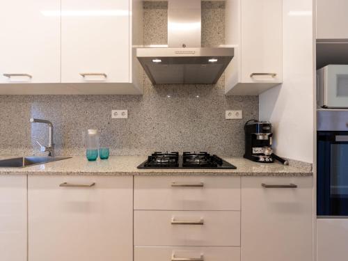 cocina con armarios blancos y fogones en Apartment Atlantis by Interhome, en Segur de Calafell