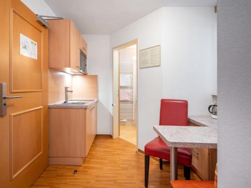 a small kitchen with a red chair and a table at Apartment Rosa-10 by Interhome in Mayrhofen