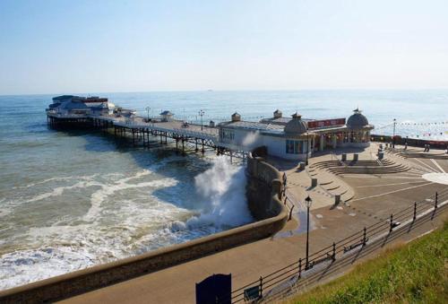 a pier with waves crashing on the beach at Miller's Loft in Erpingham