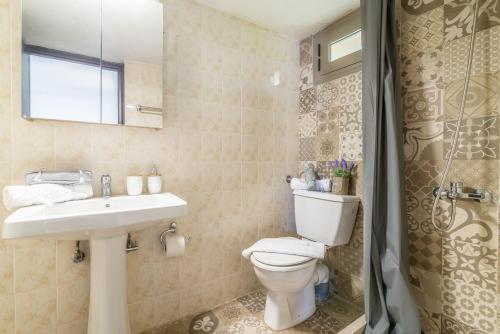 een badkamer met een toilet, een wastafel en een douche bij Ceronia Renovated House near the Beach in Palaiokastro