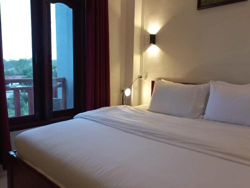 a bedroom with a large white bed with a window at Sipanya Guesthouse in Muang Phônsavan