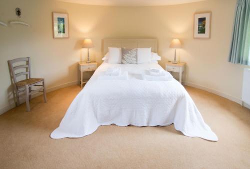 a bedroom with a large white bed with two tables at Bakers Farm Oast in Ticehurst