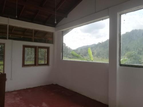 a room with two windows and a view of a mountain at Sunil's Homestay Sinharaja in Kalawana