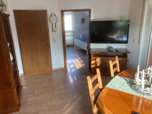 Gästezimmer zum Waldsachsener Grund في ميرانه: غرفة معيشة مع تلفزيون وطاولة طعام