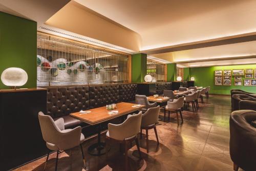 a restaurant with green walls and tables and chairs at Taj Theog Resort & Spa Shimla in Shimla