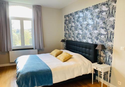 Un dormitorio con una cama con una manta azul y blanca. en L'Aubier, en Tenneville
