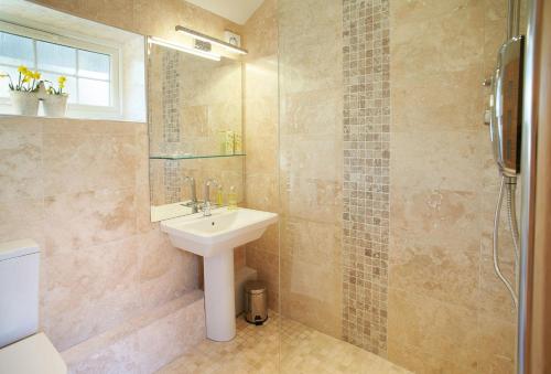 uma casa de banho com um lavatório e um chuveiro em The Cwtch em Pencoed