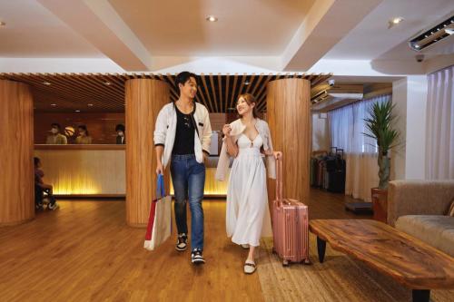 two women walking through a hotel lobby with their luggage at Arck Hotel in Bangkok