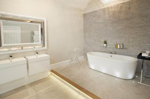 a bathroom with a large white tub and a mirror at The Potting Shed in Weston under Lizard