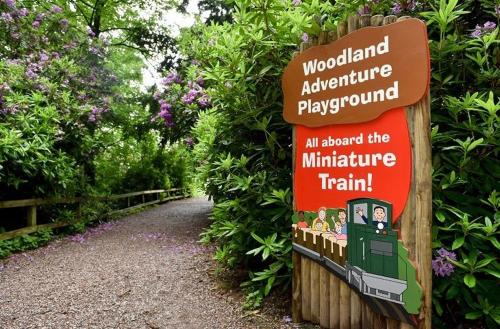 a sign for a woodland adventure playground with a train at The Potting Shed in Weston under Lizard