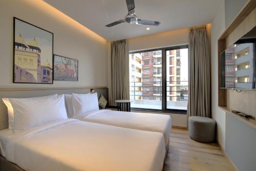 um quarto com uma cama branca e uma grande janela em 7 Apple Hotel Pratap Nagar, Jaipur em Jaipur