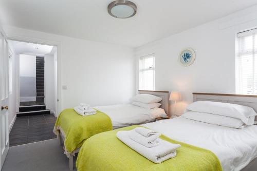 duas camas num quarto branco com toalhas em Wolf Rock em Landewednack