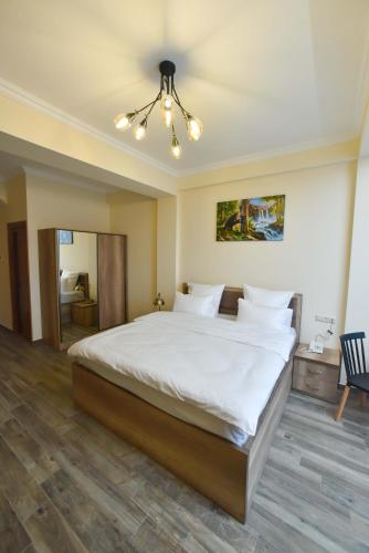 a bedroom with a large white bed with a chandelier at Altunyan Hotel in Yerevan