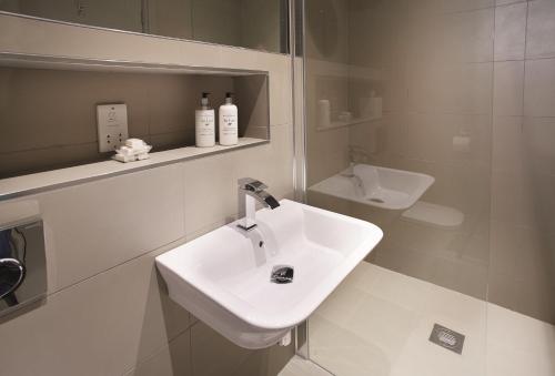 a white bathroom with a sink and a mirror at Corriedow in Thornhill