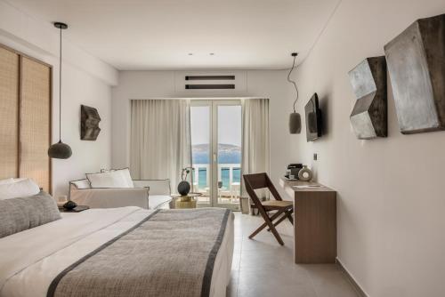 a bedroom with a bed and a desk and a couch at Grace Mykonos in Agios Stefanos