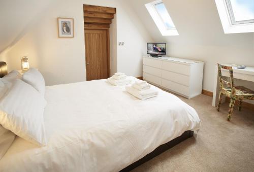 a bedroom with a white bed with a desk and a chair at Rosebank Barn in Bibury