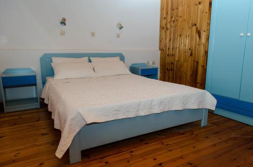a bed in a bedroom with two blue end tables at Cleopatra Studios in Marathokampos