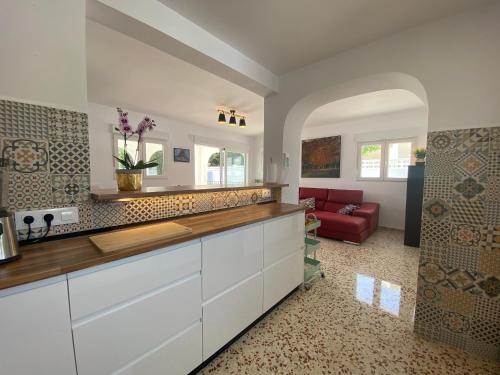 een keuken met witte kasten en een rode bank bij Villa con piscina, soleada, tranquila y céntrica in Calpe
