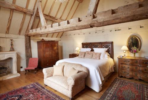 a bedroom with a large bed and a chair at Elinor Fettiplace in Pauntley