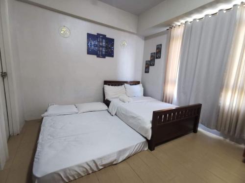 a bedroom with two beds with white sheets and a window at Entire Home @150NB pasay city in Manila