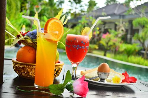 a table with two drinks and a plate of food at Pondok Wisata Sartaya 2 in Lovina