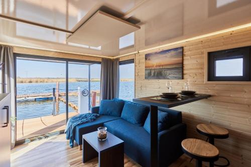 a living room with a blue couch and a view of the water at Hausboot mit Sauna Świnoujście, Houseboat Marina Karsib&oacute;r in Świnoujście