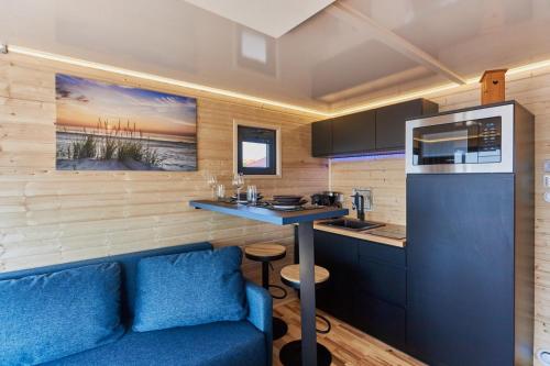 a living room with a blue couch and a kitchen at Hausboot mit Sauna Świnoujście, Houseboat Marina Karsib&oacute;r in Świnoujście