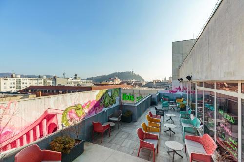 eine Terrasse mit bunten Stühlen und Tischen auf einem Gebäude in der Unterkunft ibis Styles Ljubljana Centre in Ljubljana