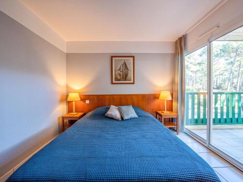 une chambre avec un lit bleu et une grande fenêtre dans l'établissement Apartment Les Grands Pins-2 by Interhome, à Carcans